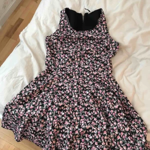  - Blommig klänning som är tight upptill och går sedan ut till en vidare kjol