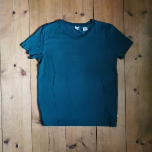 Levis  - Sparsamt använd levis tshirt i fin mörkgrön kulör. Modellen är dam modell, rätt tight i armarna och följer kroppen fint. Klippt bort lappen men tror tyget är 100% bomull. Bilderna är ej bra tagna men vill bara få ut mina plagg, om du köper plagget tvättar jag det självklart innan! 