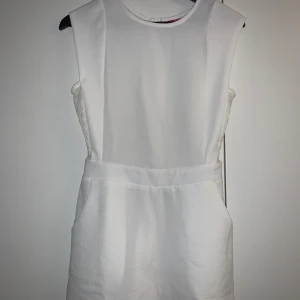 Vit jumpsuit  - Vit jumpsuit med spetsdetaljer. Storlek 38. (Mer som 36). Först till kvarn på alla plagg, ingen budgivning. Ange vilket pris du skulle vilja köpa plagget för så kan vi komma överens om ett bra pris där båda blir nöjda. 