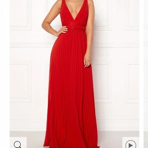 Balklänning - Säljer min balklänning som aldrig användes då balen blev inställd pga Corona. Prislappen är kvar och den är helt oanvänd. Jättefin röd färg (syns inte jättebra på bilderna). Den är låg i ryggen och banden går även att korsa om det önskas. Köptes för 1200kr, säljer den för 500kr. (Frakten ingår i priset)