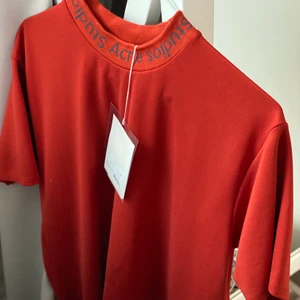 acne studios logo neck navid - Acne studios logo neck i färgen röd. Modellen heter navid. Materialet är inte bomull, utan känns lyxigare. Använd högst 2 gånger, så nästan nyskick! Nypris: 1400kr. Den är oversize. Passar mig som bär S/36 och skulle säga att den passar dem som har S/M. Kan mötas upp i innersta Stockholm, annars får köparen stå för frakten🧚‍♀️