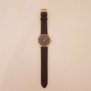  - Snygg svart klocka i läderimitarion med gulddetaljer.