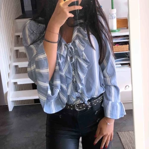 - Söt blå och vitrandig blus i skönt material med många fina detaljer. Köpt på American Eagle i Miami och sparsamt använd. (Frakt tillkommer)