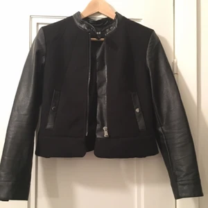  - Jättefin bikerjacka i ull- och läder imitation. Knäppning med dragkedja och knappar vid halsen. 