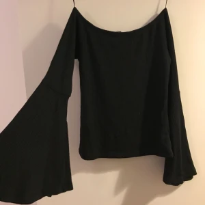  - Oanvänd. Svart ribbad off shoulder