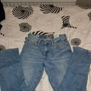 Blå jeans från Jack & Jones - Säljer ett par klassiska blå jeans från Jack & Jones. De har fem fickor, gylf med dragkedja och knapp samt raka ben. Perfekta för en avslappnad stil.