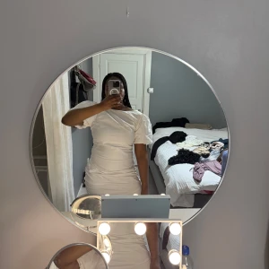 Vit puffärmad klänning med rynkade detaljer - Säljer en vit klänning med puffärmar och rynkade sidor. Klänningen har en tight passform och öppen rygg, vilket ger en snygg och modern look. Perfekt för dig som vill sticka ut med en stilren och trendig outfit.