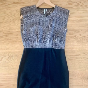 Svart och mönstrad klänning från Other Stories - Säljer en snygg svart klänning från & Other Stories med grått grafiskt mönster upptill. Klänningen är ärmlös och har en tight passform som framhäver figuren. Perfekt för dig som gillar stilrena detaljer och modern design.