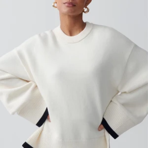 Vit stickad tröja med svarta detaljer från gina - Säljer en oversized vit stickad tröja från gina med svarta ribbade detaljer vid ärmslut och nederkant. Tröjan har rund halsringning och långa ärmar. Perfekt för en stilren och avslappnad look.