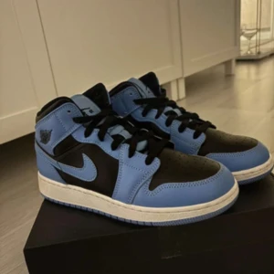 Nike Air Jordans i svart och blå - Säljer ett par Nike Air Jordans med svart och blå ovandel, vita sulor och klassisk design. Skorna har snörning och rund tå, perfekta för dig som gillar streetwear och sneakers med attityd.