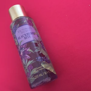 Victoria's Secret Blackberry Bite Body Mist - En body mist från Victoria's Secret med doften Blackberry Bite. Flaskan är lila med blommiga och bäriga motiv samt har ett guldfärgat lock. Innehåller 200ml och ger en fruktig och söt doftupplevelse.
