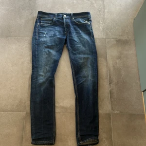 Replay jeansbyxor i blå denim - Säljer ett par klassiska blå jeans från Replay med raka ben och snygga slitningar. 