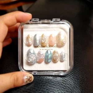 Handgjorda lösnaglar inspirerade av pärlor - Säljer ett set med handgjorda lösnaglar i olika pastellfärger och metallicnyanser. Naglarna har skimrande och pärlemorskimrande yta i silver, guld, rosa och blått. Kommer i en genomskinlig ask.
