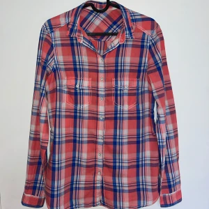 Multifärgad rutig skjorta - Säljer en rutig skjorta i rosa, blått och vitt från LINDEX. Skjortan har långa ärmar, knappar framtill och två bröstfickor med knapp. Riktigt snygg! 🌸