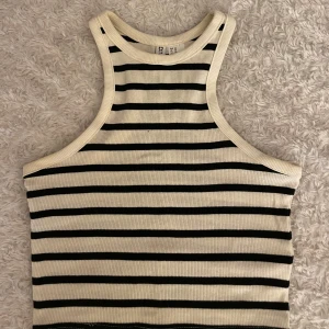 Randig ribbad linnetopp - Säljer en ribbad linnetopp med svarta och vita ränder. Toppen har en tight passform och är ärmlös med brottarrygg. 