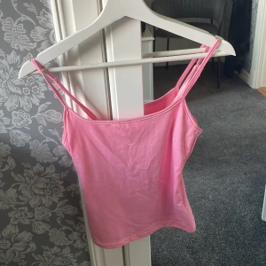 Rosa linne - Säljer en söt rosa linnetopp med smala axelband. Perfekt för varma dagar och enkel att matcha med jeans eller kjol. Toppens material känns mjukt och bekvämt mot huden.