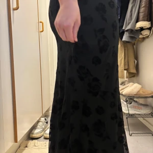 Svart långkjol med blommigt mönster från Gina Tricot - Säljer en svart långkjol från Gina Tricot med blommigt mönster. Kjolen har en figurnära passform och har resor i midjan. Supersnygg att matcha med en enkel topp. Säljer på grund av att den endast används ett fåtal gånger 🤍NYPRIS: 399 kr (priset kan diskuteras vid snabb affär 💛)