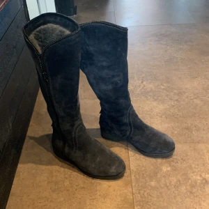 Mörkblåa fodrade Apepazza stövlar - Säljer ett par mörkblåa höga stövlar i mocka med dragkedja på sidan. Stövlarna har rund tå och platt sula, vilket gör dem både snygga och bekväma. Perfekta till höst och vinter!