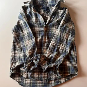 Rutig skjorta från Ralph Lauren - Säljer en snygg rutig skjorta från Ralph Lauren i blå, grön och vit. Skjortan har långa ärmar och en klassisk krage. Den är broderad med Ralph Laurens ikoniska logga på bröstet.