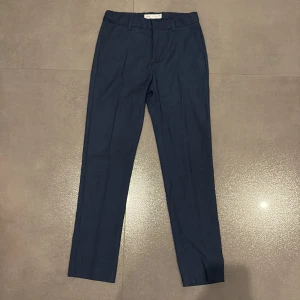 Mörkblå kostymbyxor från Zara - Snygga mörkblå kostymbyxor från Zara med klassisk rak passform och pressveck. Byxorna har hällor för bälte och diskreta bakfickor. Perfekta för en stilren look.