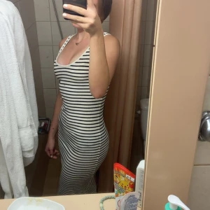 Randig ribbad långklänning från H&M - Säljer en vit och svart ribbad långklänning från H&M med smala axelband och rundad halsringning. Klänningen är tight och har ett klassiskt randigt mönster, perfekt för en stilren look. Passa perfekt på sommaren, med en tjocktröja över axlarna!