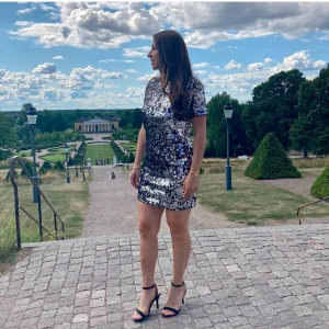 Glittrig kortklänning med paljetter - Säljer en glittrig kortklänning täckt av paljetter i silver och svart. Klänningen har korta ärmar och rak passform, perfekt för dig som vill sticka ut. Supersnygg till klackar och smycken!