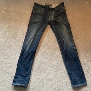 Replay Lenrick jeans i blå denim - Säljer ett par Replay Lenrick jeans i klassisk blå denim med snygga slitningar och kontrastsömmar. Byxorna har raka ben, fem fickor och detaljerade bakfickor med broderi. Perfekta för dig som gillar en tidlös jeanslook.