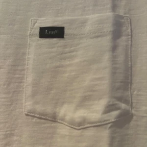 Vit långärmad tröja från Lee - Säljer en stilren vit långärmad tröja från Lee med rund halsringning och en bröstficka med diskret logga. Tröjan har en normal passform och är tillverkad i mjuk bomull, perfekt för en enkel och clean look. Nypris ca 600-700kr mitt pris 225kr. Kontakta vid frågor, skick: ny testad en gång.