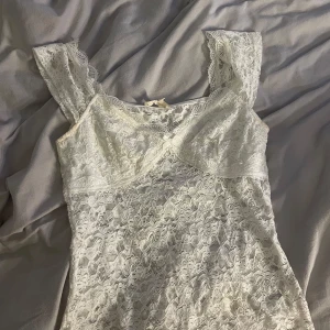 Vit spetslinne från Missäy - Säljer ett vitt spetslinne från Missäy i storlek S/M men sitter mer som en XS. Linnet har breda axelband och är helt täckt av vacker spets med fina detaljer. Perfekt för dig som gillar romantisk och feminin stil.