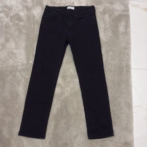 Svarta jeansbyxor från Pier One - Säljer ett par svarta jeansbyxor från Pier One. Klassisk femficksmodell med normal passform och raka ben. Byxorna har knapp och dragkedja framtill samt bälteshällor. Perfekta till många olika stilar.