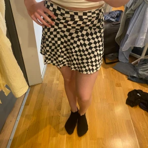 Svartvit rutig kjol från H&M - Säljer en svartvit kortkjol från H&M med ett coolt rutigt mönster. Kjolen har en lätt utsvängd form och resår i midjan för en bekväm passform. Perfekt för dig som gillar statement-plagg och vill sticka ut lite extra.❤️Katt finns i hemmet