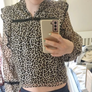 Leopard printad Blus med volanger från lindex  - Fin trendig Blus med leopard print och volanger. Tunt tyg på ärmarna och tjockare over magen. Svarta trädetaljer. Knappar öppe vid halsen. Perfekt nu för våren och sommaren. Har användit några gånger men i nyskick.  Frakt ingår inte. Säljer för att jag har växt ur dem. 
