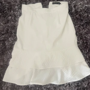 Vit volangkjol från STOCKH LM - Säljer en söt vit kjol från STOCKH LM i storlek 34. Kjolen har volangdetalj nertill och en lätt utsvängd form. Perfekt för dig som gillar en feminin och stilren look.