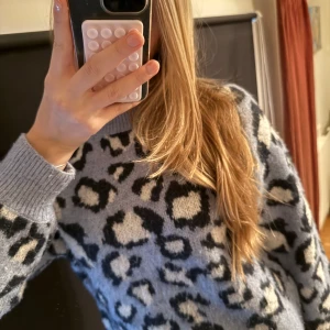 Leopardmönstrad stickad tröja från Mango - Säljer en supermjuk stickad tröja från Mango i storlek XS. Tröjan är ljusblå med svart och vitt leopardmönster, har rund hals och långa ärmar med breda ribbade muddar. Bra skick men har blivit lite nopprig. Köpt i Paris.