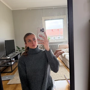 Mörkgrå polotröja - Säljer en mörkgrå polotröja med lång ärm och lös passform. Tröjan är stickad och har en hög polokrage som ger en mysig känsla. Perfekt för kyligare dagar och enkel att styla till olika outfits.