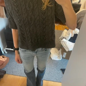 Grå kabelstickad tröja med kort ärm - Säljer en grå kabelstickad tröja med korta ärmar och rund hals. Perfekt nu till sommaren med shorts eller jeans 