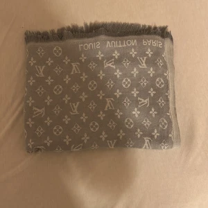 Grå och Ljusgrå Louis Vuitton halsduk - Säljer en lyxig grå halsduk från Louis Vuitton med klassiskt monogrammönster och fransad kant. Perfekt accessoar för att lyfta din outfit med en exklusiv touch. Märket syns tydligt invävt i kanten. Den har både en grå och en ljusgrå sida. Hör gärna av dig vid intresse😁