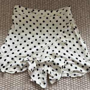 Vit prickig kjol/shorts från Zara - Supersöta vita shorts från Zara med svarta prickar och volangkant. Använd enstaka gånger och så söt till sommaren! 