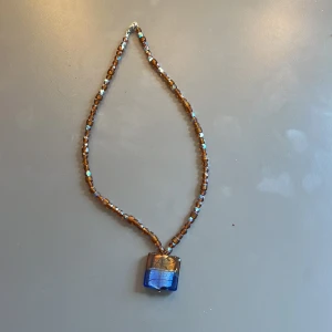 Halsband med bruna/blå pärlor och ett hänge - Ett handgjord halsband med bruna oärlor som skiftar lite i blått med ett brun/blått hänge.