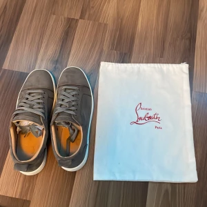 Gråa sneakers från Christian Louboutin - Säljer detta par  gråa Christian Louboutin då de tyvärr inte passar mig. Skorna har små tecken på användning men är inget man tänker på. De är i storlek 45. OBS lådan medföljer ej. 