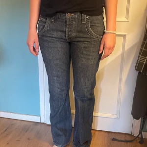 Lågmidjade wrangler bootcut jeans mörkblå strl 32x32 - Säljer ett par mörkblå bootcut/raka jeans från Wrangler. Klassisk femficksmodell med snygga kontrastsömmar och detaljerade bakfickor. Jeansen har normal passform och är perfekta för dig som gillar en tidlös look. Midjemått: 43 cm rakt över. Innerbenslängd: ca 75,5 cm