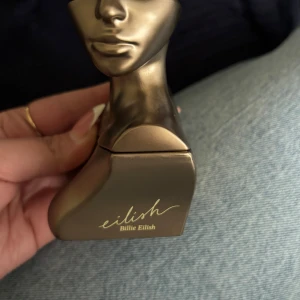 Eilish parfym av Billie Eilish - Säljer en Eilish parfym av Billie Eilish. Flaskan är formad som en byst och har en snygg metallisk guldig färg. Materialet är hård plast eller metall-look. Flaskan rymmer 50 ml och har en unik, konstnärlig design som sticker ut i parfymhyllan.