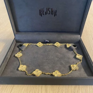 Guldigt blommigt halsband från Kejsar - Supersnyggt halsband från Kejsar i guldton med flera små blommor längs kedjan. Blommorna har fina detaljer och ger ett lyxigt intryck. Perfekt accessoar för att lyfta din outfit med en elegant touch.