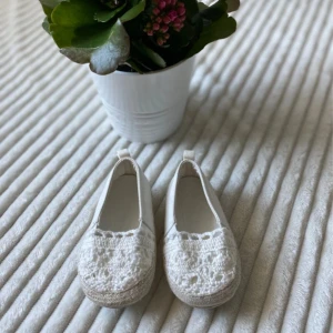 Vita virkade ballerinaskor H&M, barn 18-19 - Söta vita ballerinaskor från H&M i storlek 18-19. Skorna har en virkad ovandel och platt sula, perfekta för vår och sommar. De har rund tå och en liten ögla bak för enkel påtagning. Superfina till små fötter!