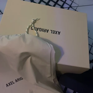 Svarta sneakers från Axel Arigato - Stilrena svarta sneakers från Axel Arigato i mocka med platt sula och rund tå. Skorna har diskret logga på sidan och klassisk snörning. Perfekta för dig som gillar minimalistisk och clean stil. Aldrig använda bara testade. Säljer eftersom dem var för små. Nypris runt 2500 kr säljer för endast 750 kr . Allt på bilden hänger med ! 