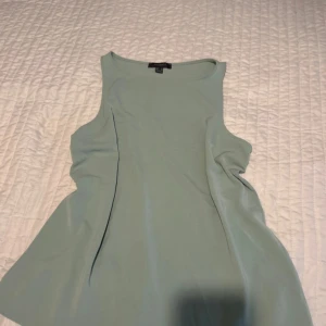 Ljusgrön ärmlös topp från Primark - Snygg ljusgrön ärmlös topp från Primark i enkel och stilren design. Toppen har rund halsringning och lätt utsvängd passform, perfekt för en fräsch och clean look. Tillverkad i mjukt material som känns skönt mot huden.