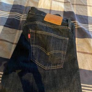 Levi's 501 mörkblå jeans W32 L34 - Klassiska Levi's 501 jeans i mörkblå denim med raka ben och femficksmodell. Snygga kontrastsömmar och ikonisk röd Levi's-tagg på bakfickan. Perfekta för dig som gillar tidlös stil och vill ha ett par jeans som funkar till allt.