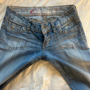 Lågmidjade jeans med slitningar -  Midjemått: 38cm, Innerbenslängden: 84cm Snygga ljusblå jeans från Esprit med bootcut passform och klassisk femficksdesign. Jeansen har låg midja, slitna detaljer och dekorativa bakfickor med knappar. PRIS KAN DISKUTERAS 