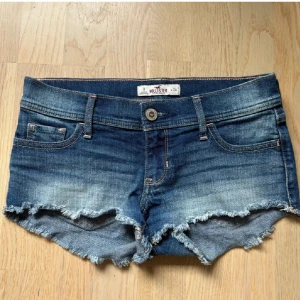 Blå jeansshorts från Hollister - Säljer dessa lågmidjade jeansshorts från hollister, perfekta till sommaren. Nyskick -knappt använda storlek W24 men är stretchiga och passar fler storlekar. Midjemått tvärs över 37cm 🥰