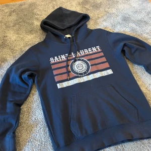 Saint Laurent Hoodie - Hej, vi säljer denna feta hoodie från Saint Laurent! Skick: 9/10 knappt använd! Storlek: M men passar även S. Tveka inte på att kontakta oss om du har några frågor eller funderingar💯